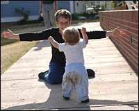 A woman about to embrace a toddler